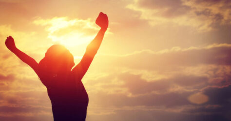 strong confident woman open arms to sunrise at sea